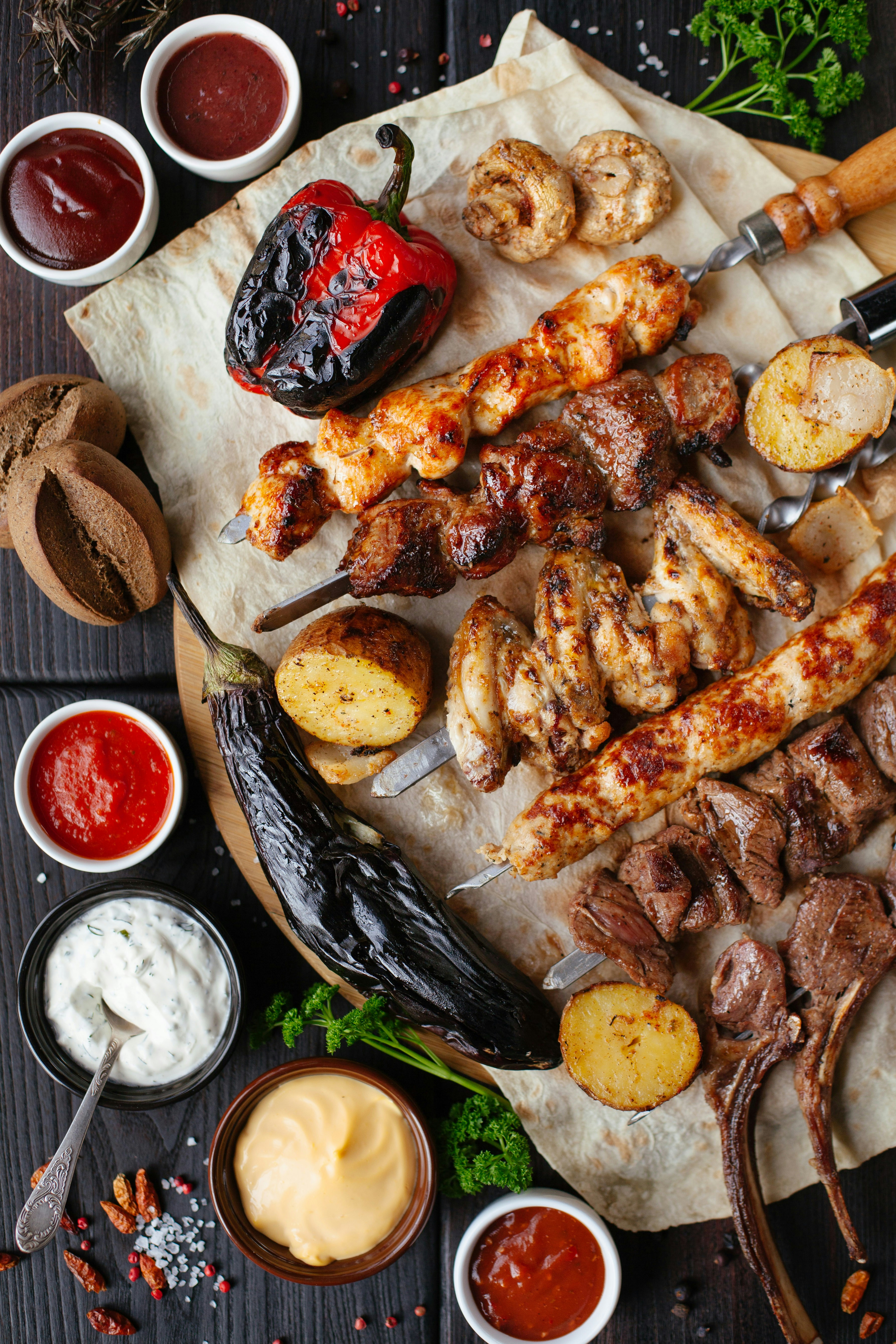 Assorted grilled meat skewers, roasted vegetables, and dipping sauces from Darbar Restaurant's BBQ kitchen